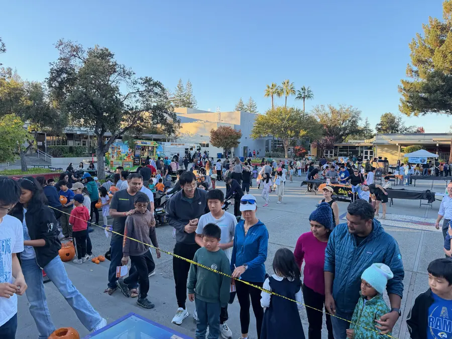 Families streaming through the courtyard past the taped-off smash zone, with a food truck and rows of booths behind them.
